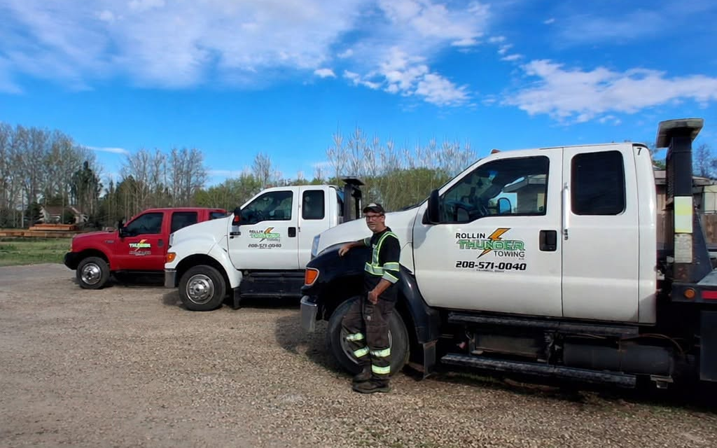 David standing beside three Rollin Thunder Towing trucks in Caldwell, Idaho.